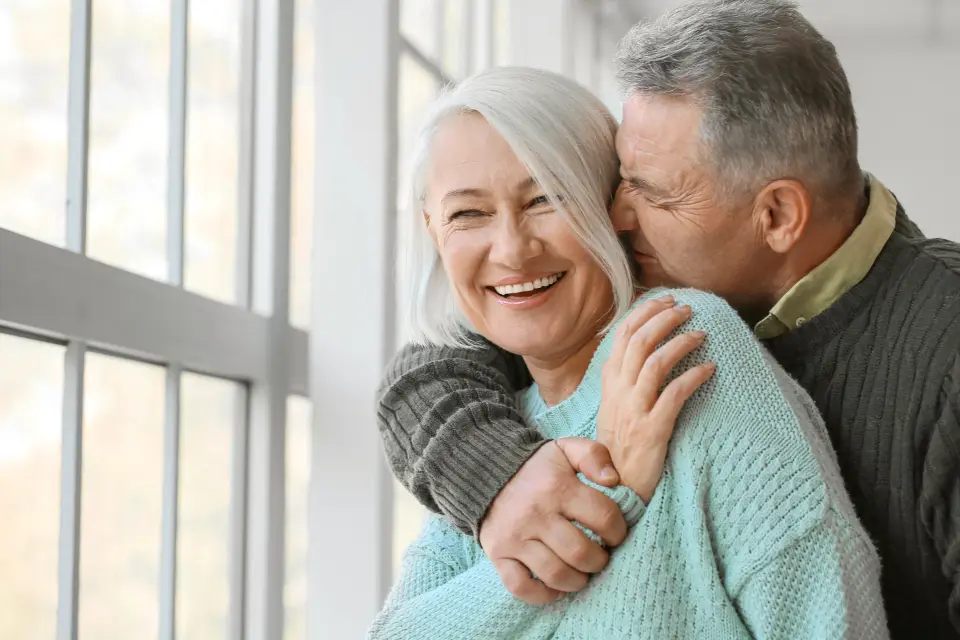 Smiling older couple at home by a bright window